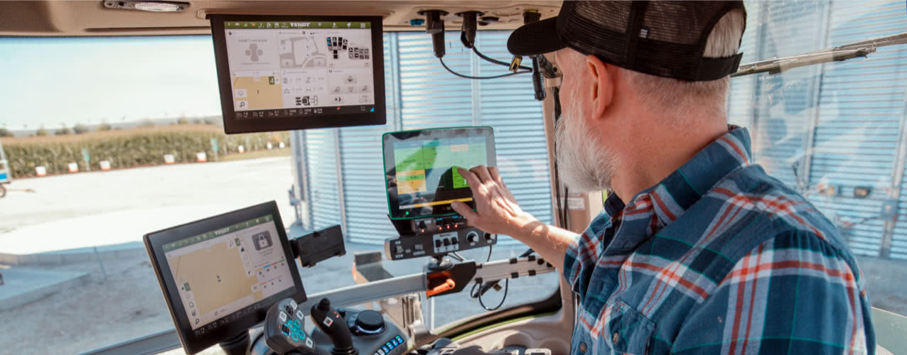 A man operates multiple screens from within a tractor cab
